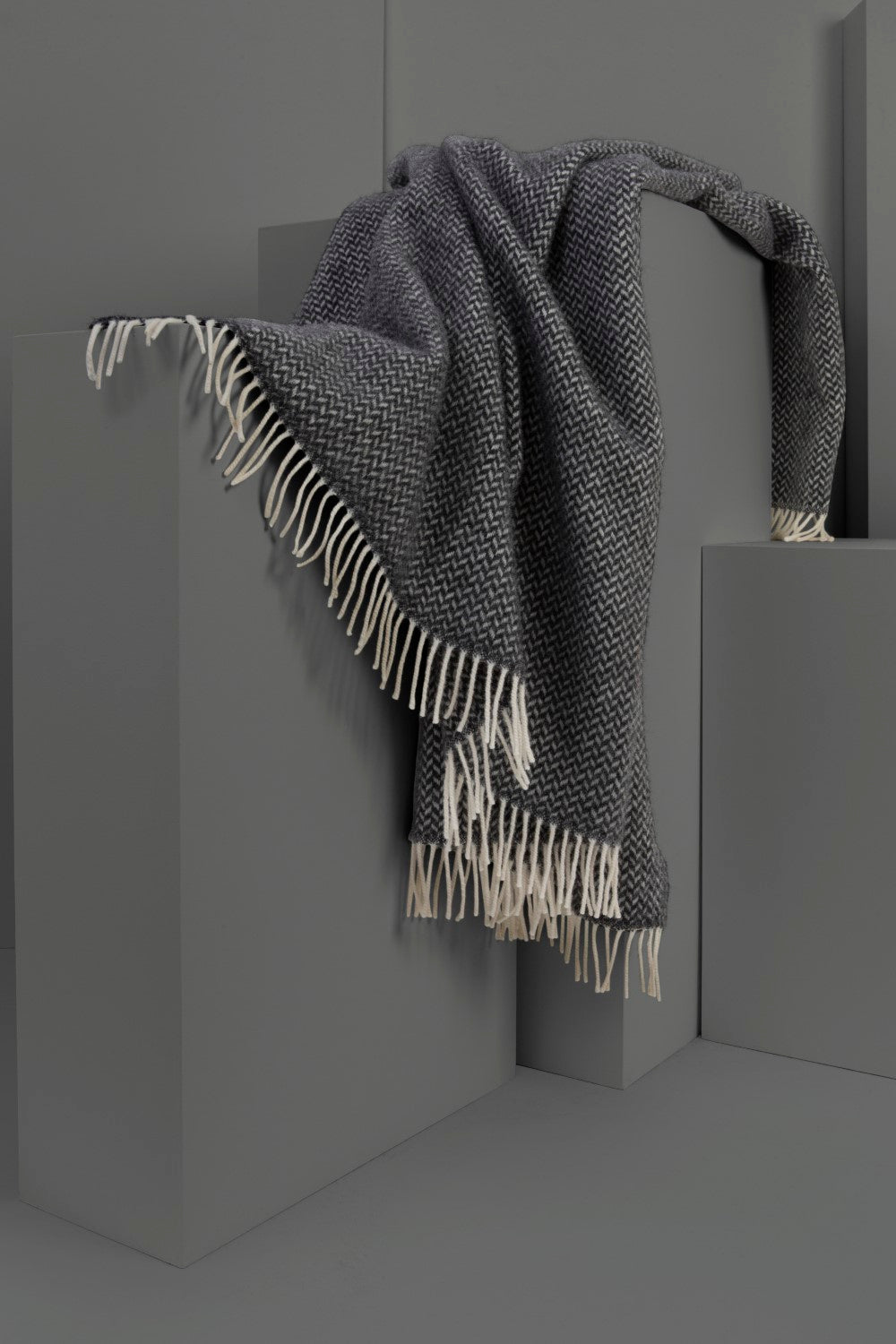 Grey herringbone wool blanket draped over large display plinths.