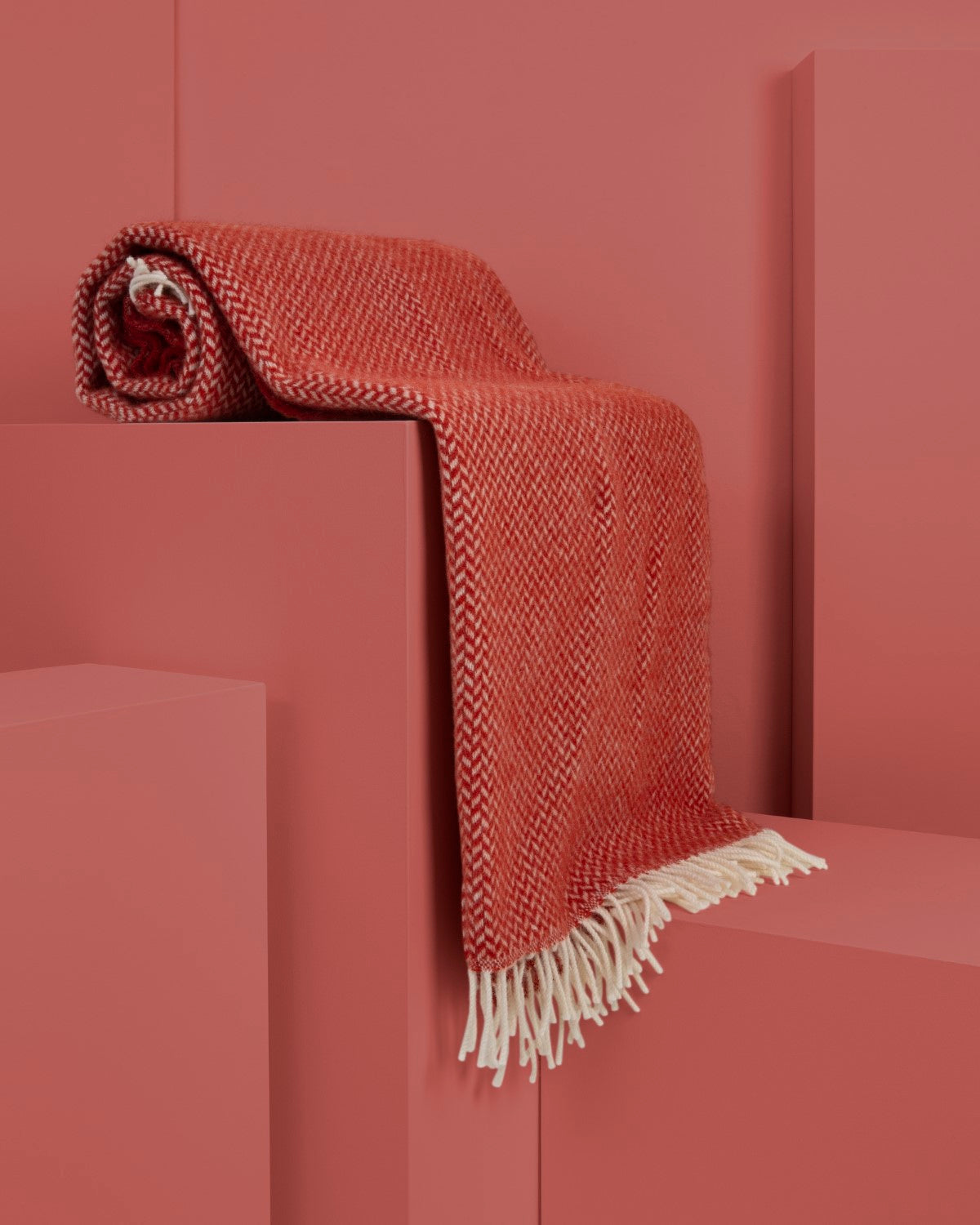 Semi-rolled red herringbone wool blanket draped over display plinths