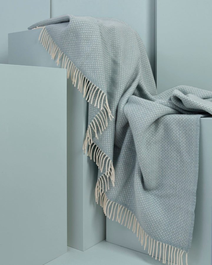 XL blue herringbone wool blanket draped over display plinths