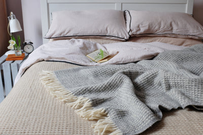 An extra large cream waffle wool blanket spread across a bed