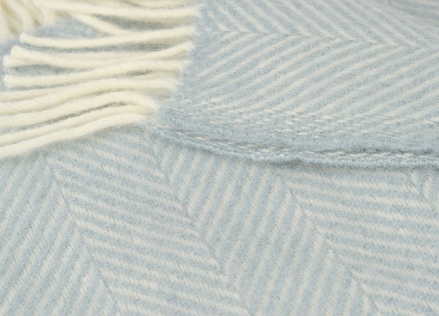 Closeup of duck egg blue herringbone wool throw by The British Blanket Company.