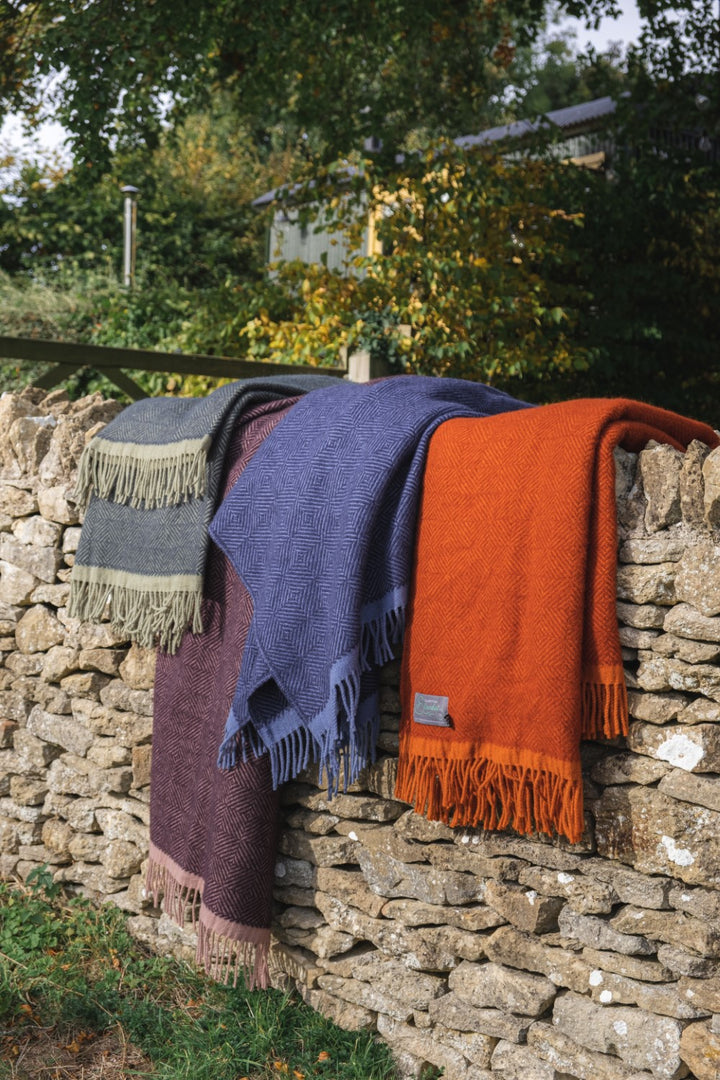 Several folded wool blankets draped over a stone fence