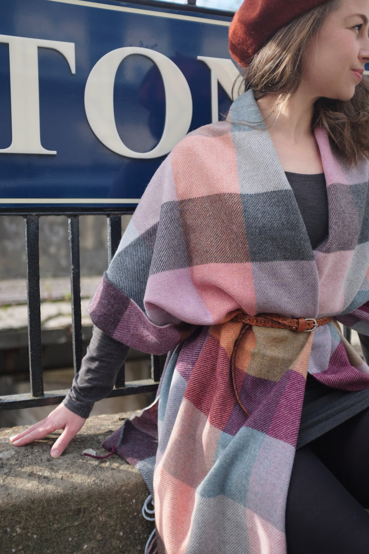 A woman wearing an oversized wool blanket scarf in various colours. 