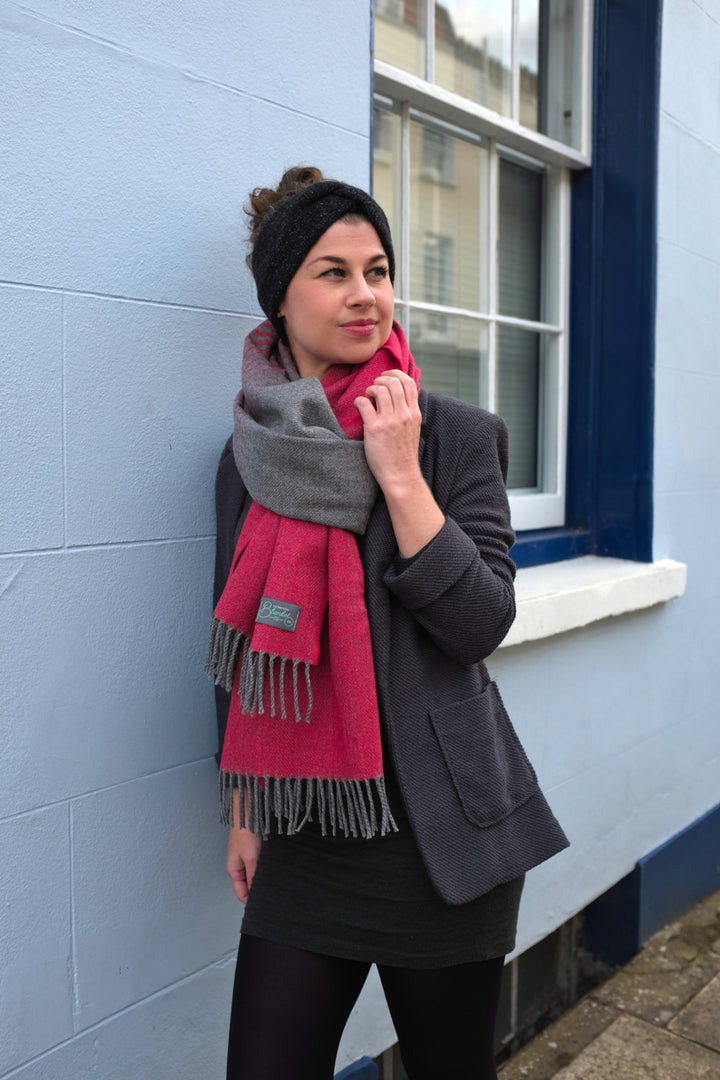 A woman wearing a red and grey merino wool oversized blanket scarf around her neck