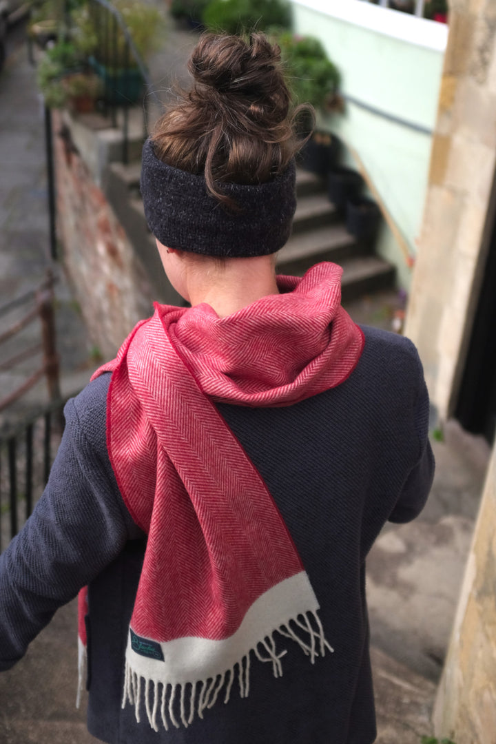 A woman wearing a red herringbone lambswool scarf walking down the stairs