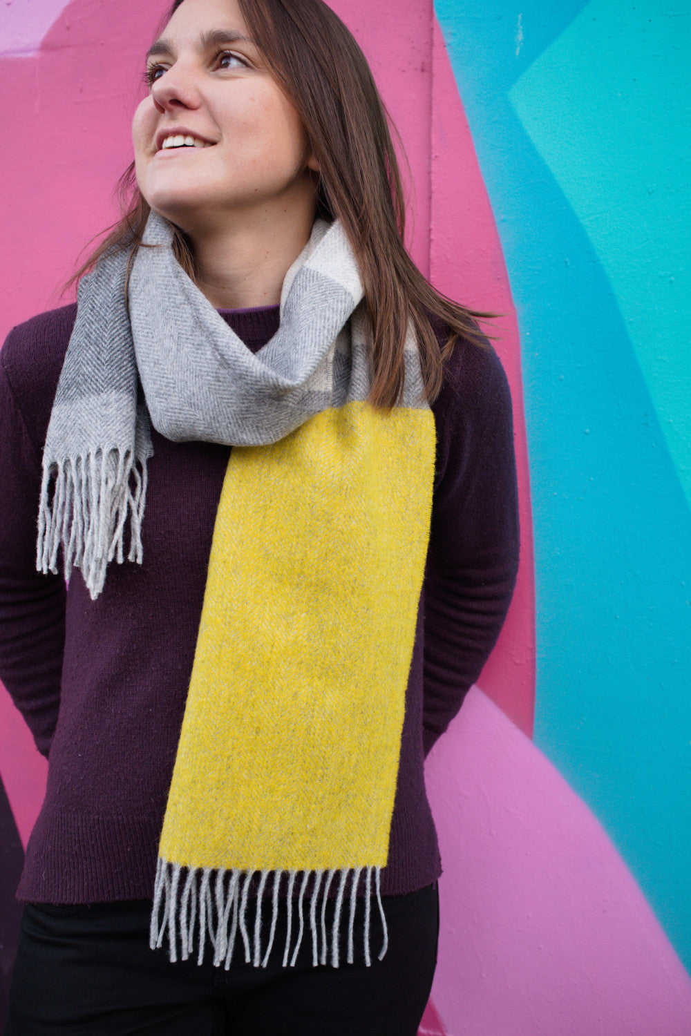A woman wearing a yellow and grey lambswool scarf around her neck.