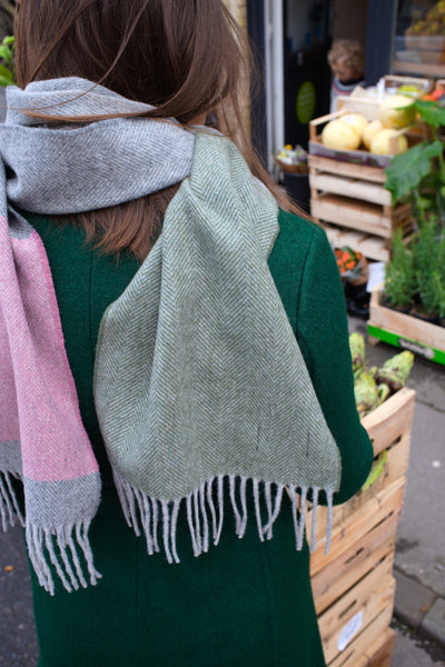 Closeup of a woman wearing a green, grey, and pink lambswool scarf.