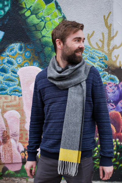 A man wearing a grey and yellow lambswool scarf over his shoulder