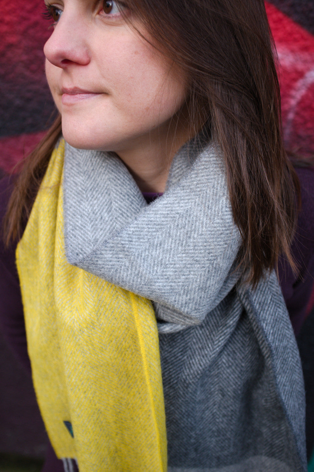 Closeup of a woman wearing a yellow and grey lambswool scarf by The British Blanket Company.