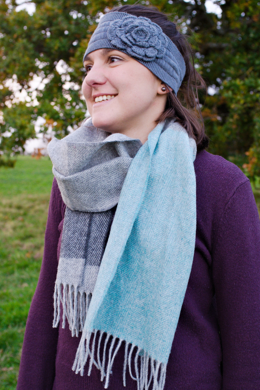A woman wearing a grey and blue lambswool scarf wrapped around her neck. 