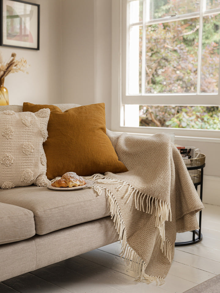 Beige beehive wool blanket draped on beige sofa