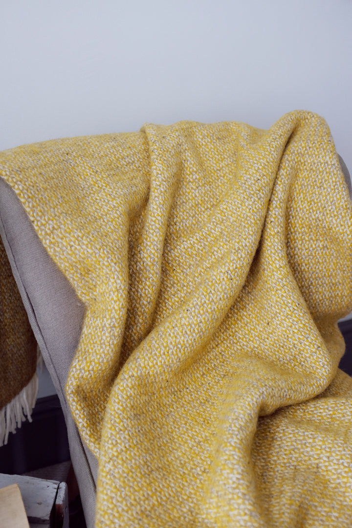 Closeup of a large yellow and grey windmill wool blanket on a lounge chair