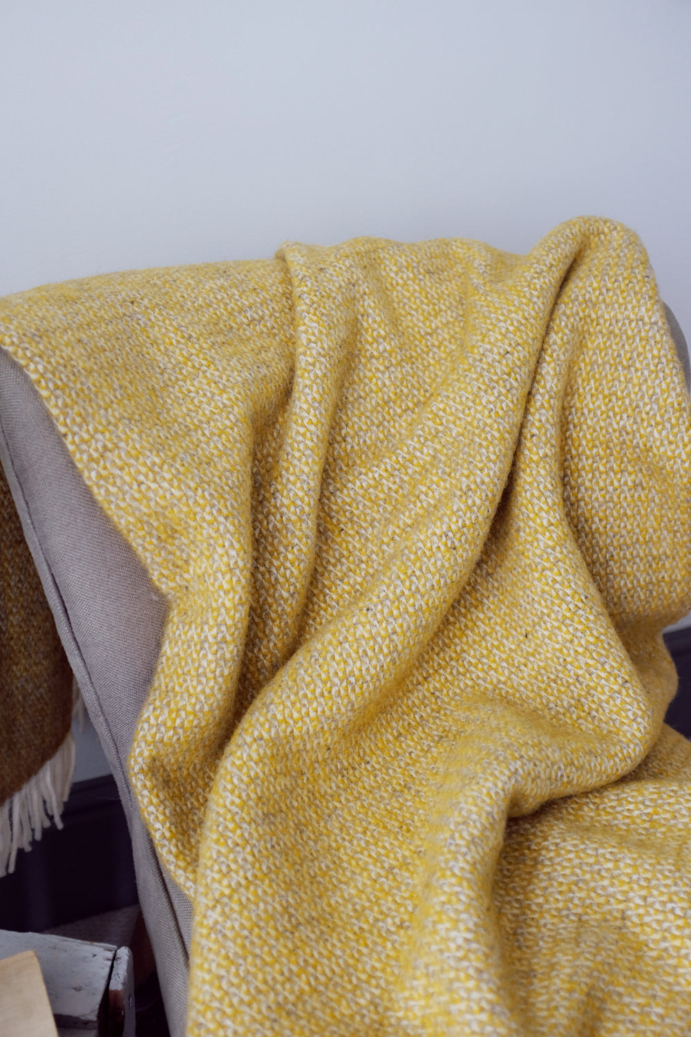 Closeup of a large yellow and grey windmill wool blanket on a lounge chair