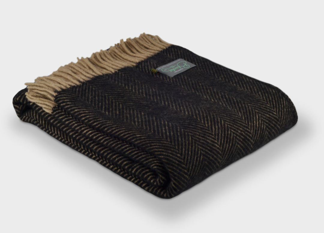 A folded black herringbone wool blanket by The British Blanket Company.