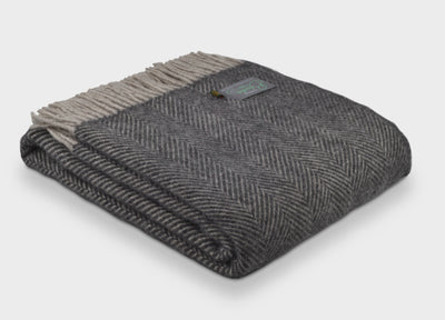 A folded grey herringbone wool throw by The British Blanket Company. 