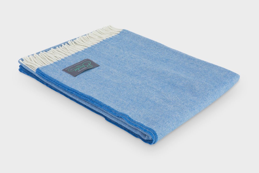Folded blue merino herringbone wool throw by The British Blanket Company.