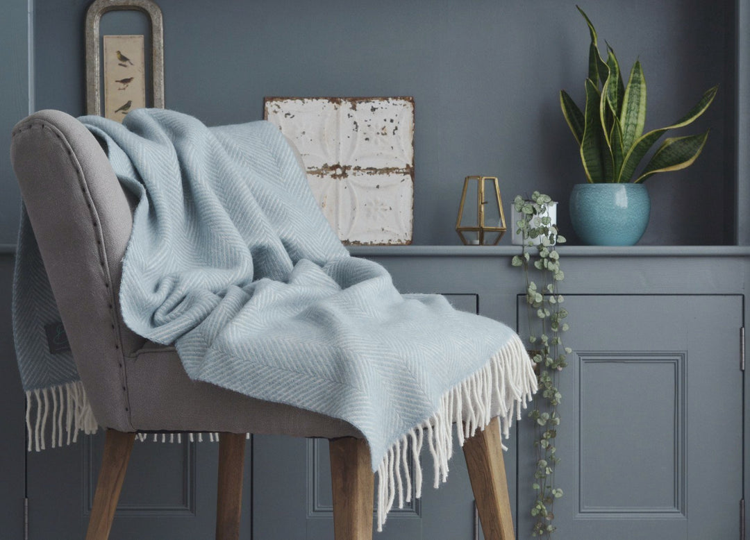 Light blue herringbone wool blanket draped over a lounge chair.