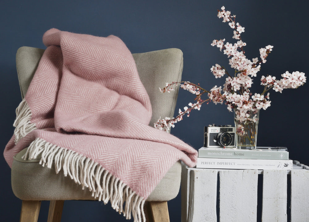 Large pink herringbone wool blanket draped over a grey lounge chair.