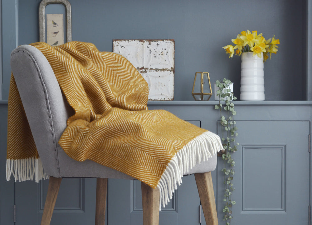 Yellow herringbone wool blanket draped over grey lounge chair