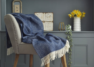 Navy blue herringbone wool blanket draped over a lounge chair