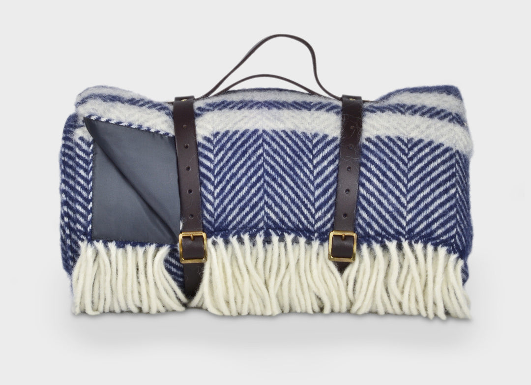 Blue and grey wool picnic rug by The British Blanket Company rolled up with leather straps