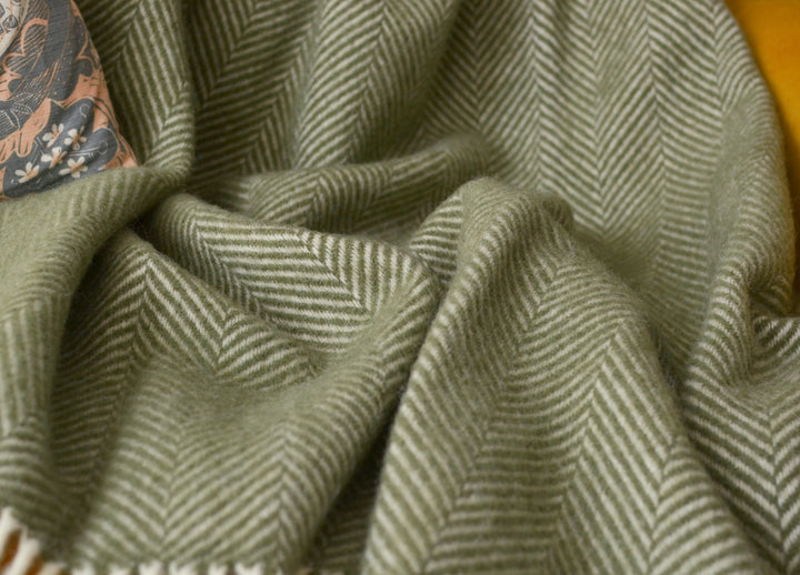 Closeup of an extra large olive green herringbone wool throw