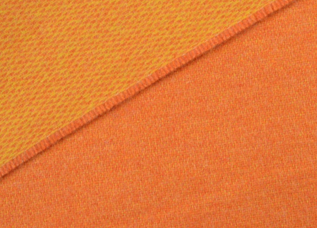 Closeup of an orange and yellow reversible merino wool blanket