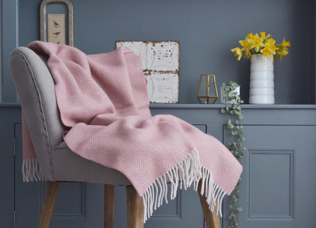 Pink herringbone wool blanket draped over a lounge chair.