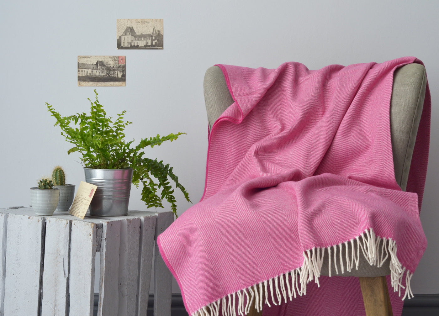 Large pink merino herringbone wool blanket draped over a lounge chair