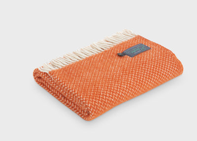 Folded orange herringbone wool throw by The British Blanket Company