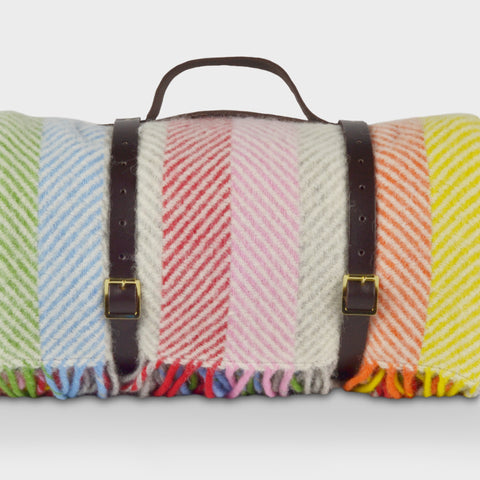 Rainbow stripe wool picnic rug by The British Blanket Company rolled up with leather straps