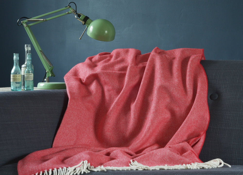 Large red merino herringbone wool blanket draped over a sofa