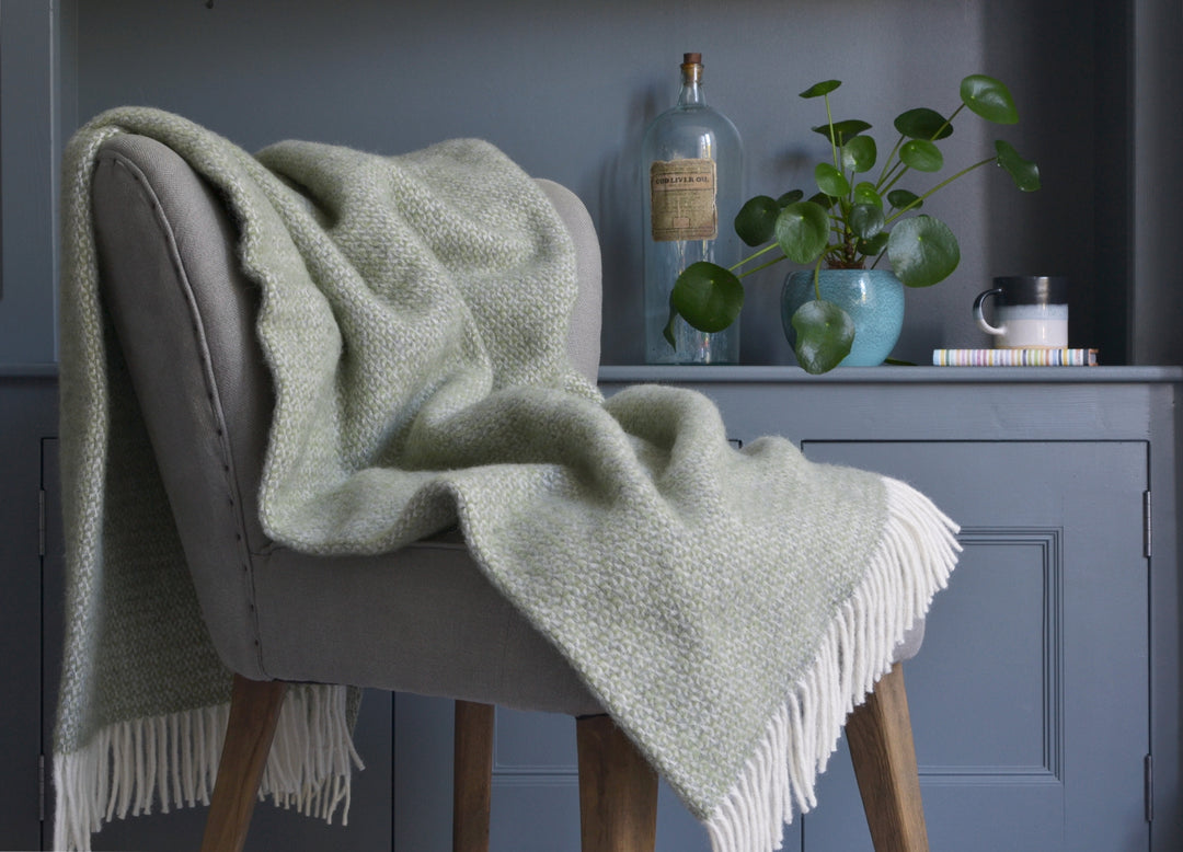 Large green and grey windmill wool blanket draped over a lounge chair