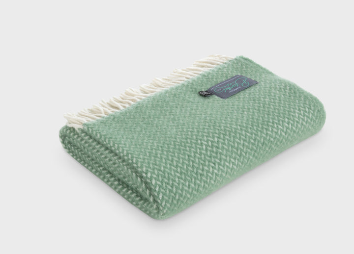 Folded green herringbone wool throw by The British Blanket Company