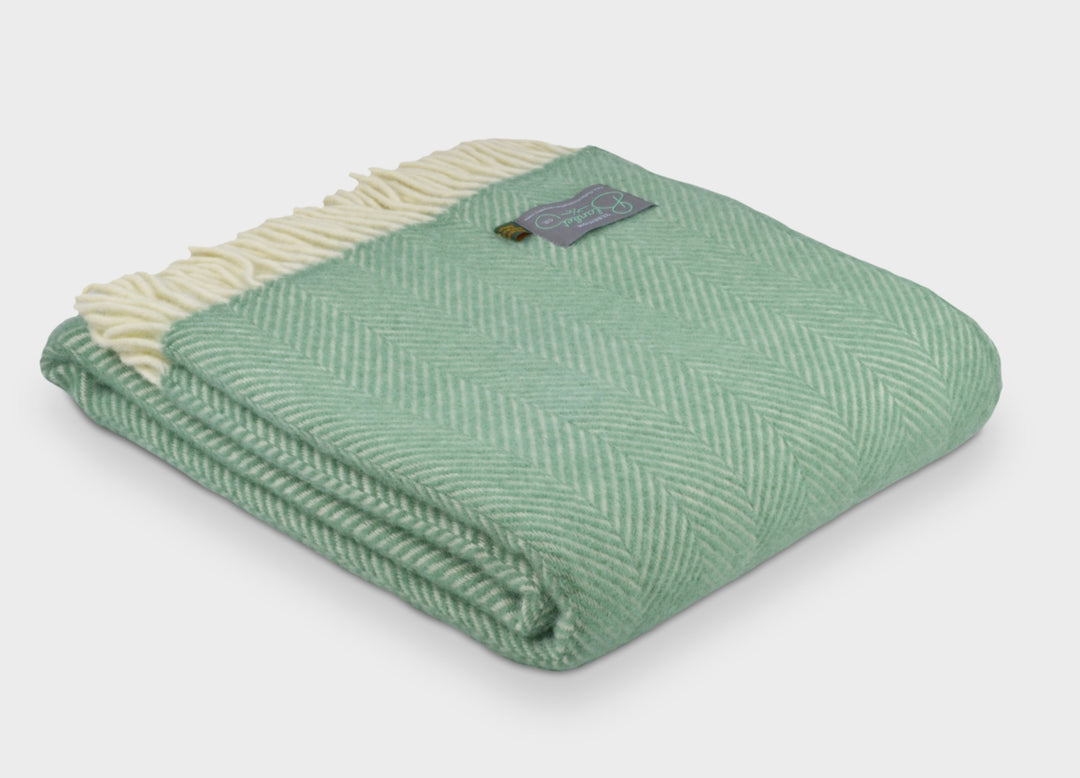 Folded large green herringbone wool throw by The British Blanket Company