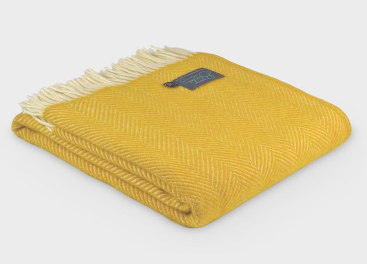 A folded yellow herringbone wool throw by The British Blanket Company. 